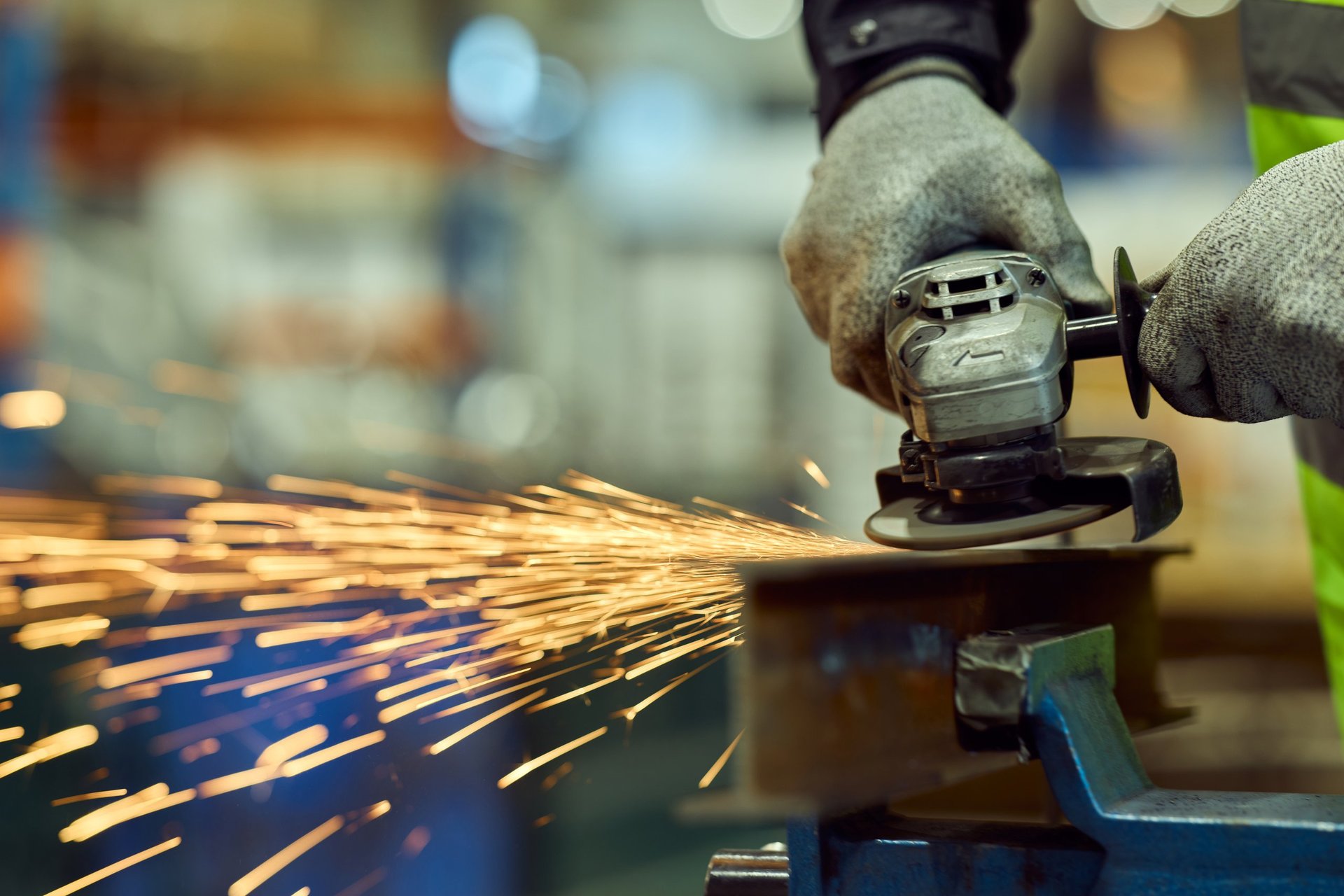 Skilled factory worker grinding metal producing bright sparks