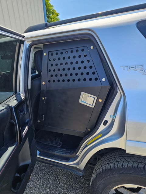 Open door of a pickup truck showing a black perforated metal security panel or dog cage inside the vehicle cabin