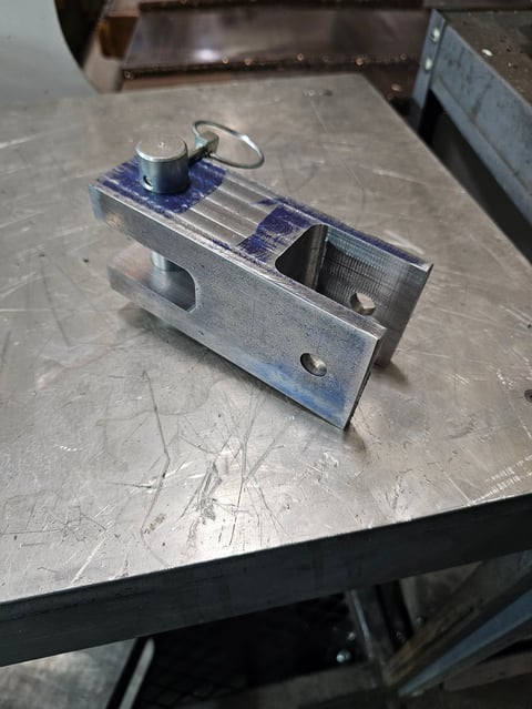 Metal vise with blue painted sections mounted on a workbench with metal surfaces