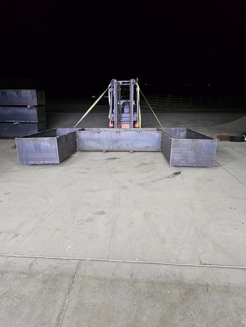 Metal livestock loading ramp with side gates on concrete surface at night