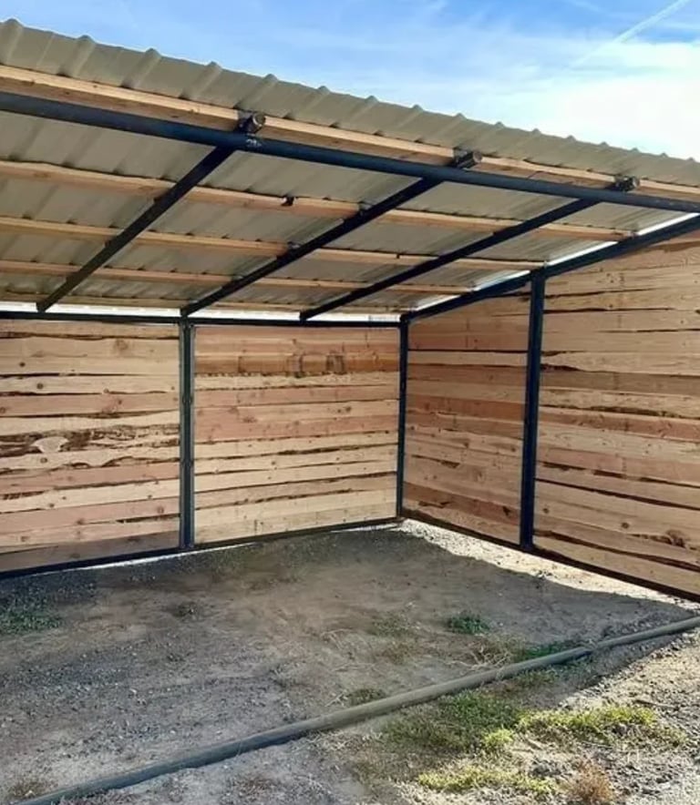 Modern carport with metal frame and roof, wooden horizontal siding walls, and gravel floor in open construction