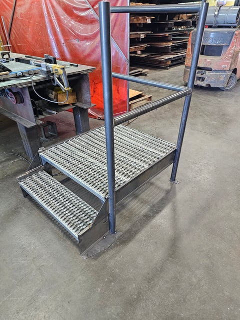 Industrial metal work platform with blue steel frame and perforated steel steps in a warehouse setting