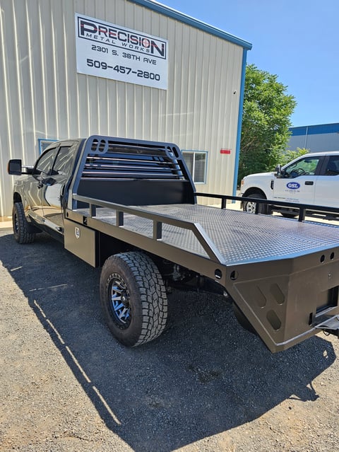 Tan pickup truck with custom flatbed and toolbox parked outside Precision automotive shop building